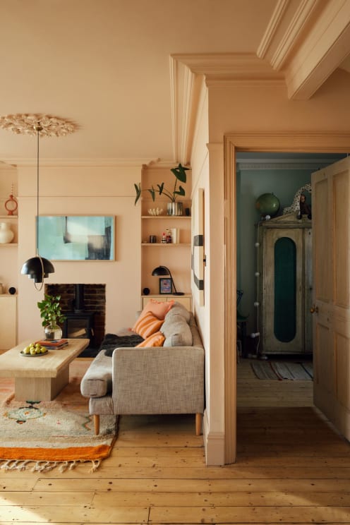 Living Room With Sofa, Fireplace, And Wall Shelves, Floral Chandelier Overhead, Leading To Room With Antique Wardrobe