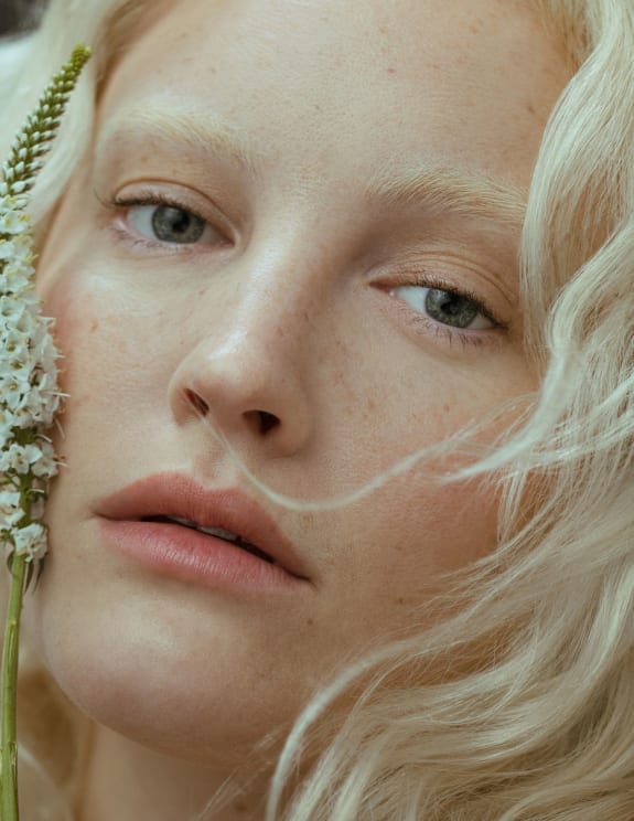 A Young Blonde Woman Looks Ahead With Flowers On Her Cheek