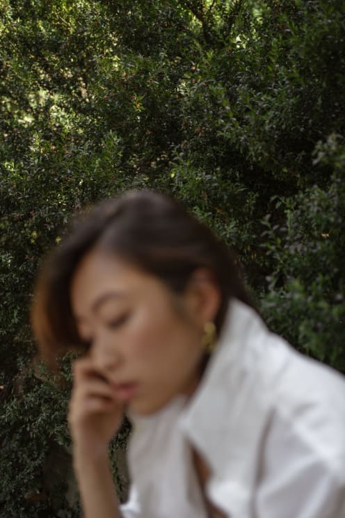 A Portrait Of A Woman Sitting Outdoors On A Sunny Day
