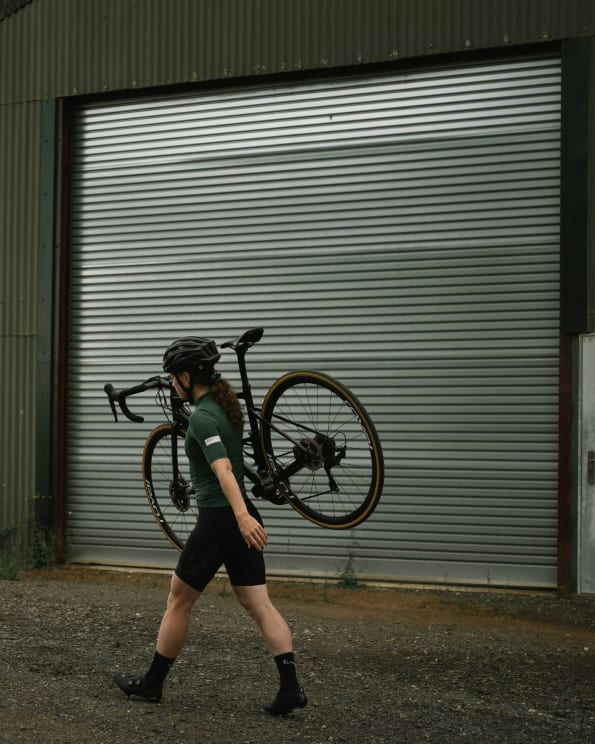A Female Cyclist Carrying Her Bike On Her Shoulder While Walking In The Street