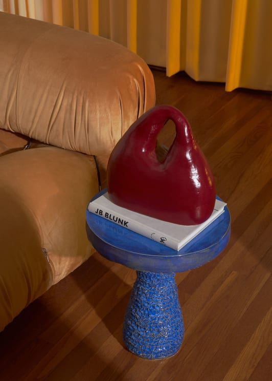 Red Sculpture And White Book Sit On Blue Pedestal In Living Room