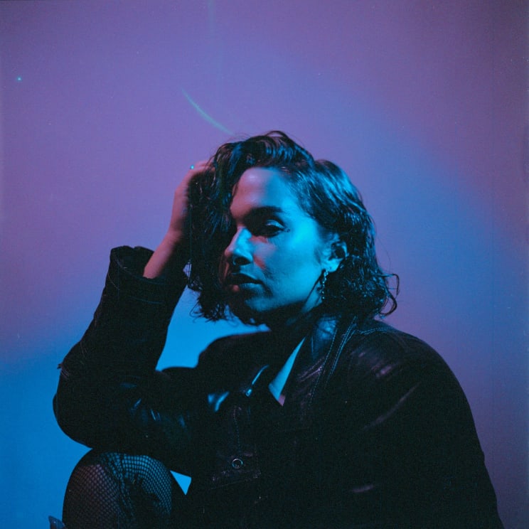 A Young Woman Looks Contemplative As She Holds Her Hand To Her Head While Wearing A Leather Jacket