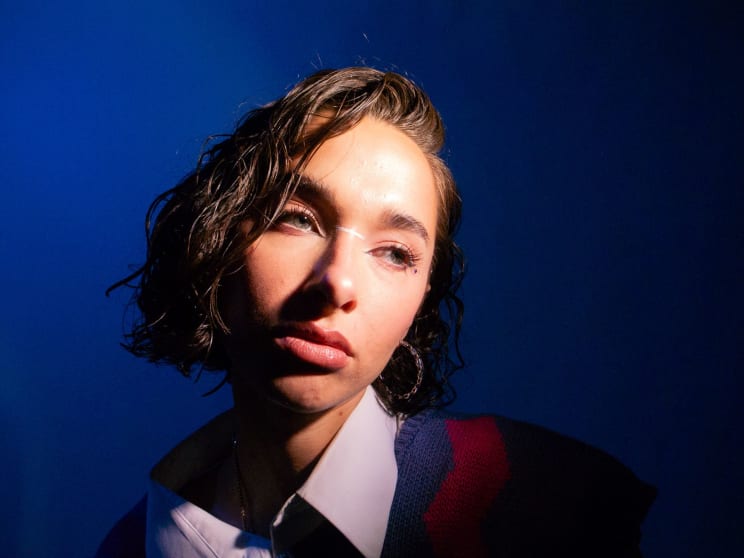Portrait Of A Young Woman With A Beam Of Light On Her Face Against A Blue Background