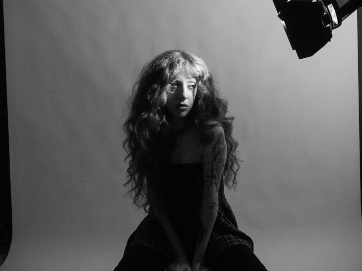 A Young Woman With Curly Hair Siting Under Studio Lights