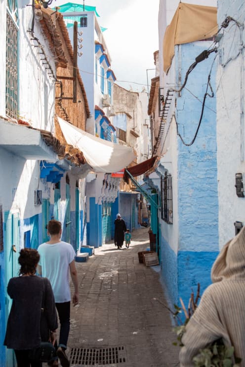 Urban Alley With Blue And White Residential Walls And Pedestrians Walking