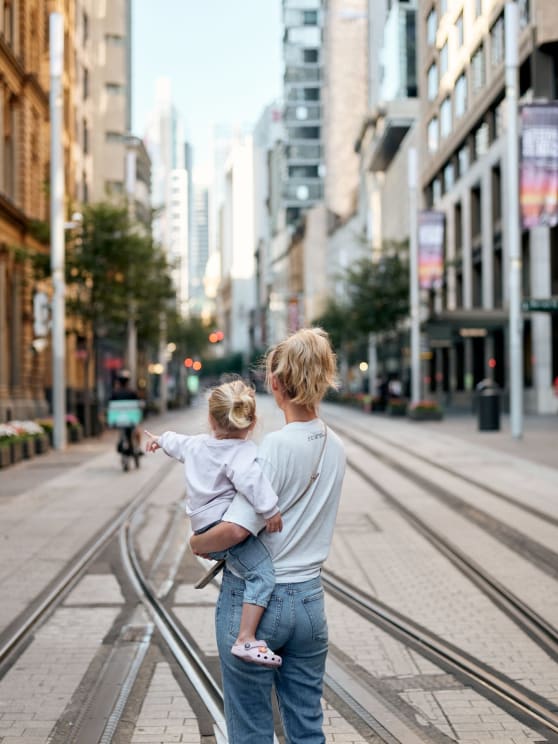 Woman Standing On A City Street Holding Her Little Girl In Her Arms