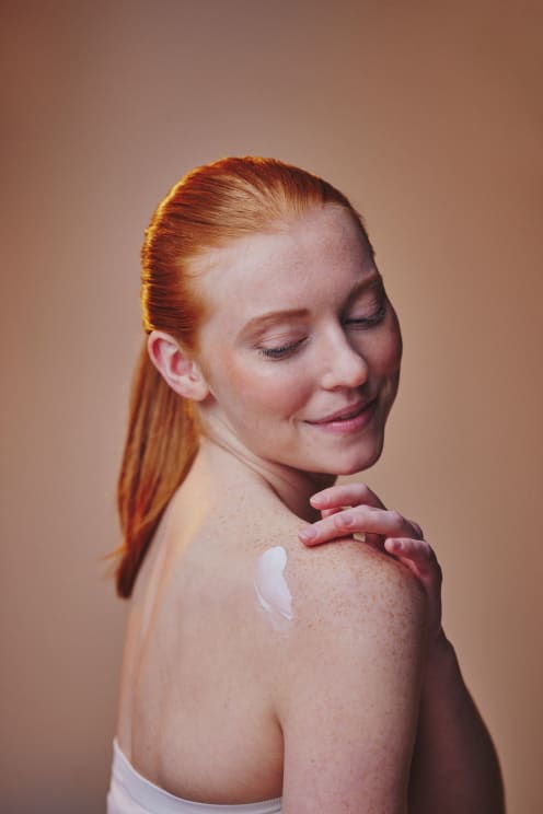 A Woman Putting Lotion On Her Shoulders