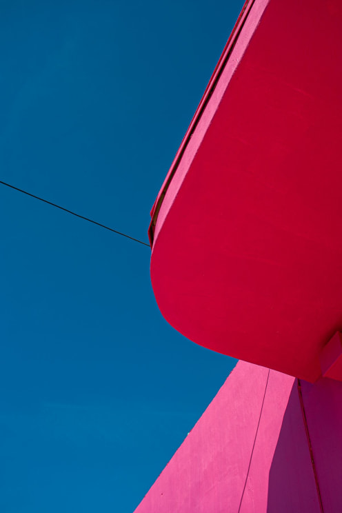 Red Roof And Pink Wall Stand Out Against A Clear Blue Sky