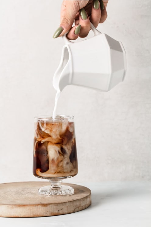 Woman Is Pouring Cream Into A Drink