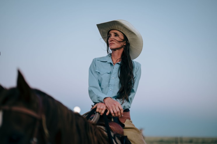 Woman With Long Dark Hair Wearing A Cowboy Hat Is Sitting On Her Horse