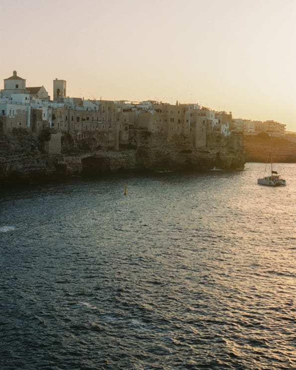 A Picturesque Coastal Town At Sunset With A Boat In The Water