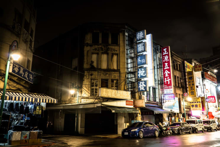 Cars Parked Along A Downtown Street Illuminated By Street Lights And Signs