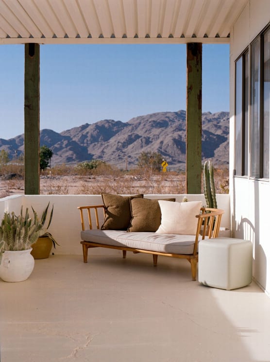 A Cozy Outdoor Seating Area With A Wooden Bench, Cushions And Plants, Overlooking A Picturesque Mountain Landscape