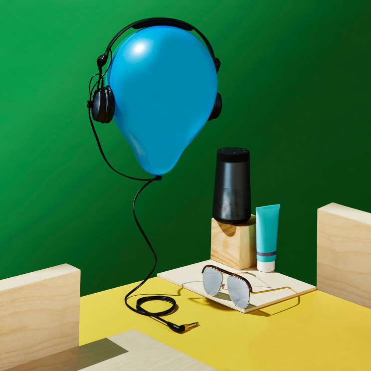 Blue Balloon With Headphones, A Speaker, Sunglasses And Beauty Products On A Surface
