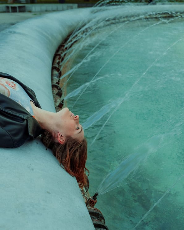 A Woman With Red Hair Lies On Her Back On The Pool Ledge