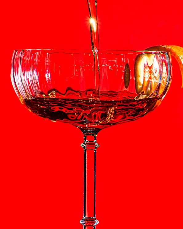 Drink Being Poured Into A Cocktail Glass Against A Vibrant Red Background