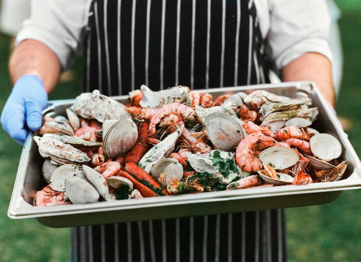 A Person Holding A Platter Full Of Seafood
