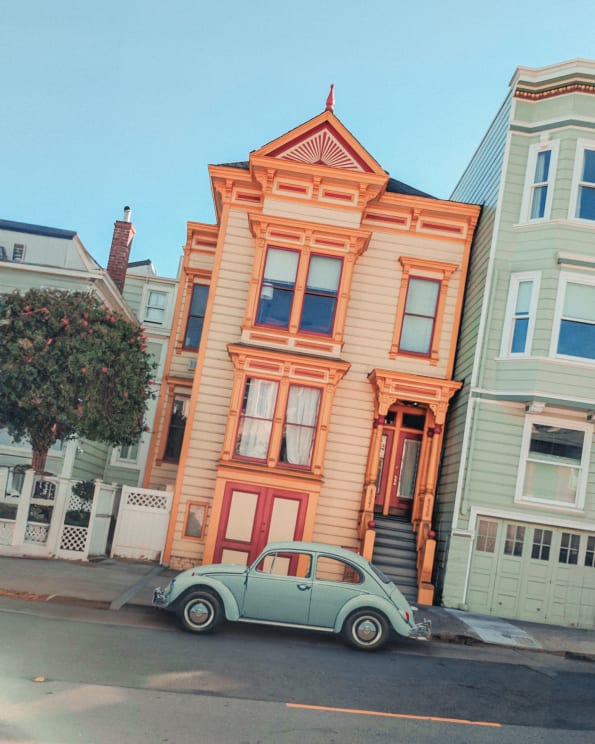 A Volkswagen Beetle Parked In Front Of An Orange Town House