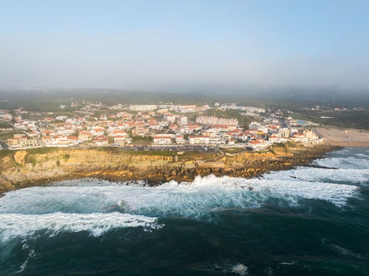 A Coastal Town With Identical Houses Overlooks The Wavy Ocean