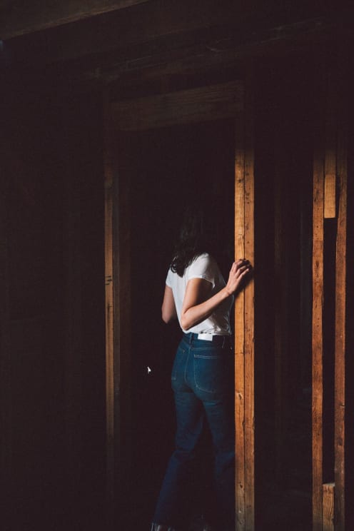 A Woman In Jeans And A White Shirt Stands In An Unfinished Room