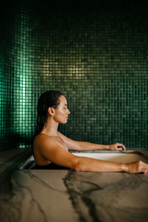 Woman Relaxing In A Bathtub With Green Tiles In The Background