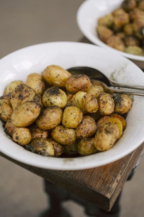 A Bowl Of Roasted Potatoes Rests On A Wood Plank