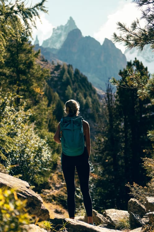 A Backpacker Standing In The Woods, Looking Onto A Mountain Track