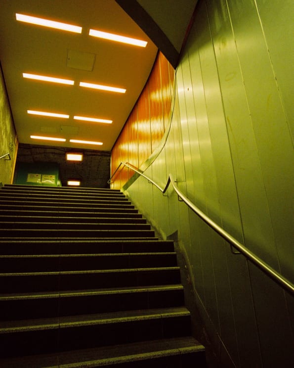 A Subway Station Staircase With Yellow Lighting And Metal Walls
