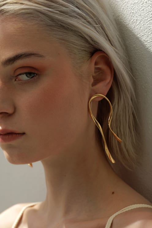 A Young Woman With Platinum Hair And An Elegant Gold Earring, Looking In Profile