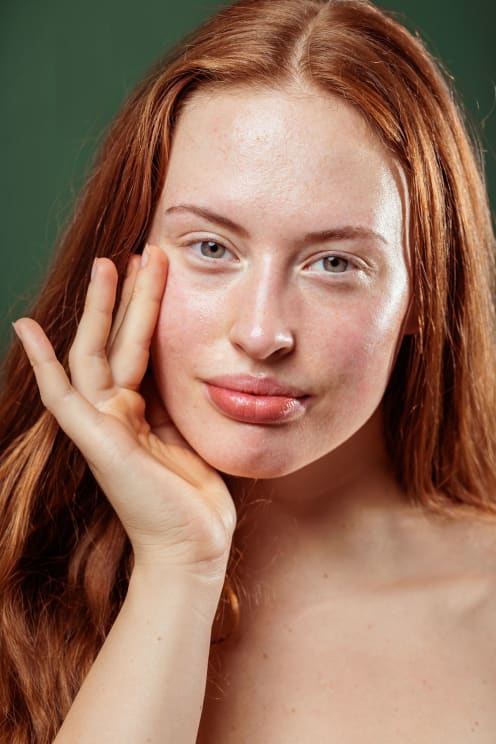 Close-up Of A Young Woman With Long Red Hair Who Touches Her Hand To Her Face