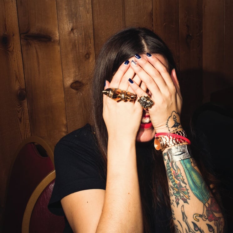 A Young Girl With A Tattoo On Her Left Arm Covering Her Face As She Laughs