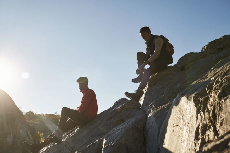 Two People Sitting On Sunlit Rocks, Enjoying The Outdoors