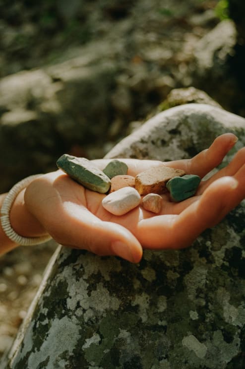 A Woman Gently Cradles Smooth Stones In Her Hands Over A Large Rock