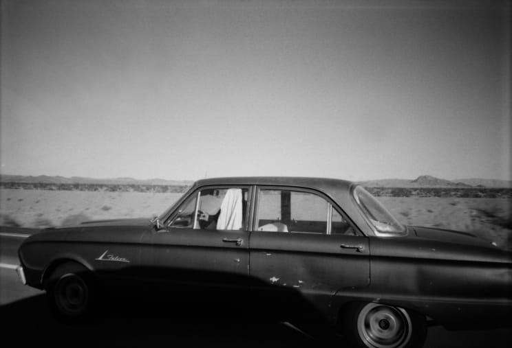 Vintage Car On A Road With A Desert Landscape In The Background