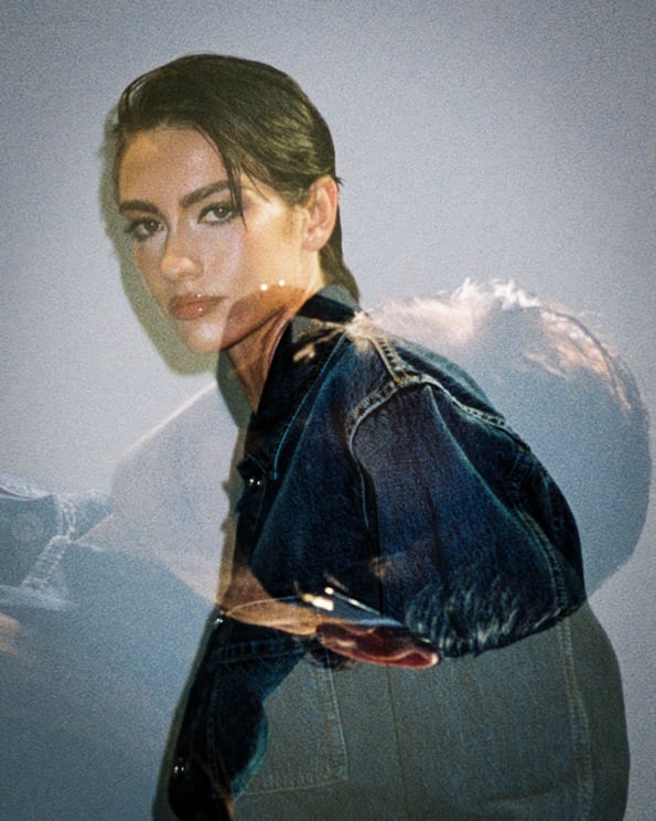 A Young Woman Modeling Jean Clothing Overlays A Larger Image Of Her Face