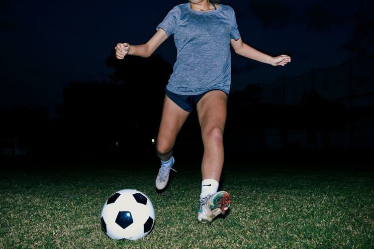 Woman In Position To Shoot A Soccer Ball On Grass At Night