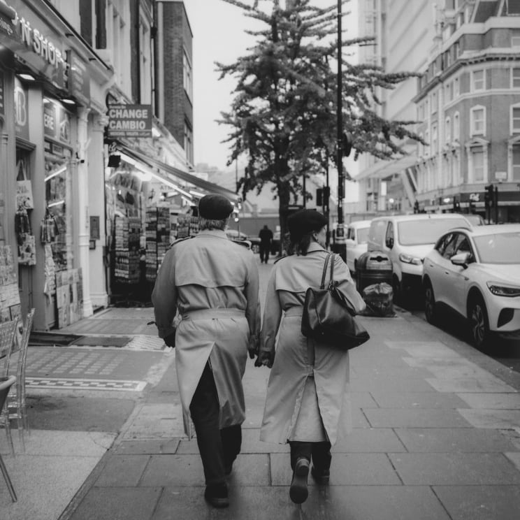 Two People Walking Hand In Hand On A City Sidewalk