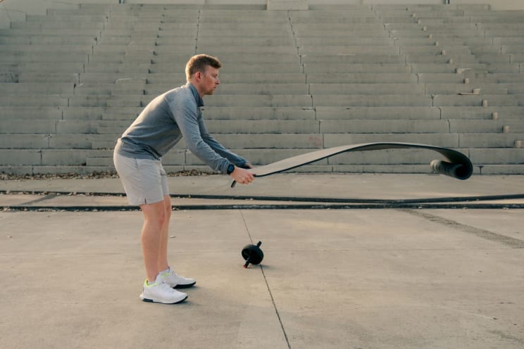 A Man Is Stretching Out A Yoga Mat Outdoors