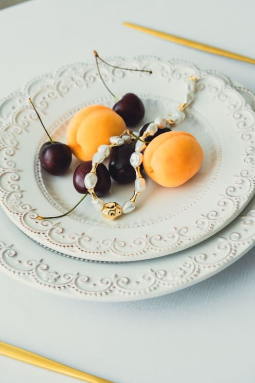 Two Plates With Cherries, Peaches, And A Necklace Or Bracelet On Them