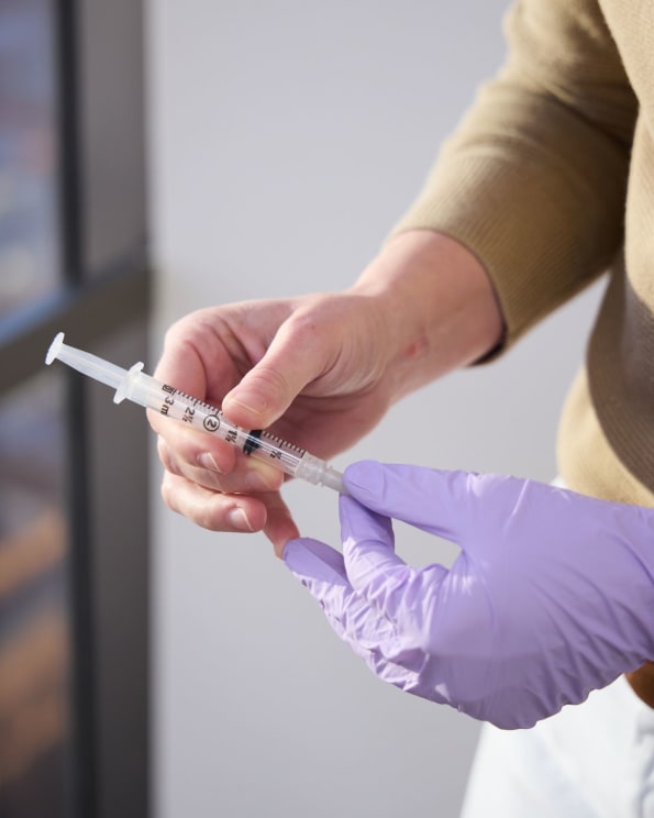 Hand With A Purple Glove Holding A Syringe