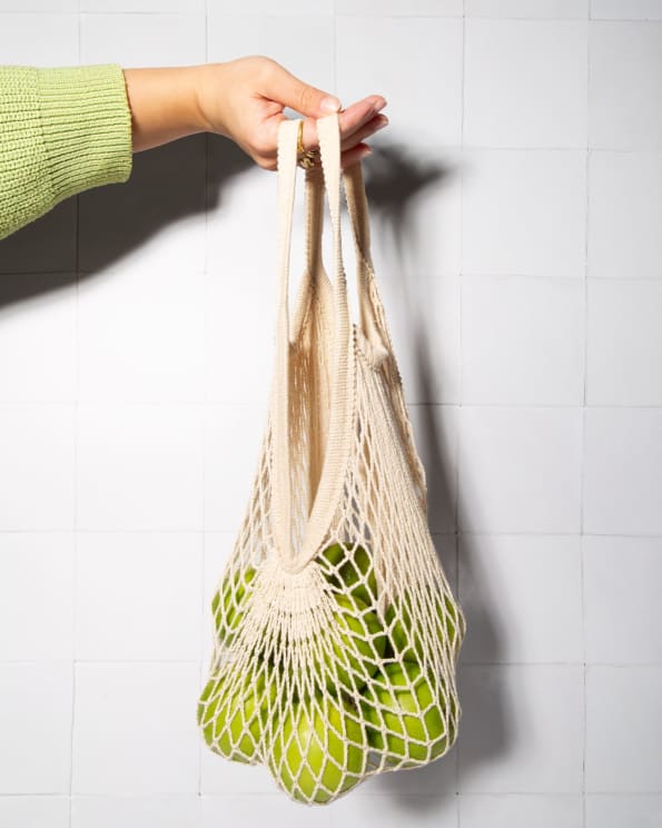 A Woman Holding A Bag Full Of Limes