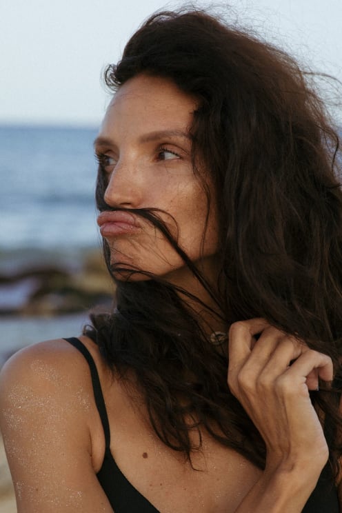 A Woman Playing With Her Hair Outside On A Beach