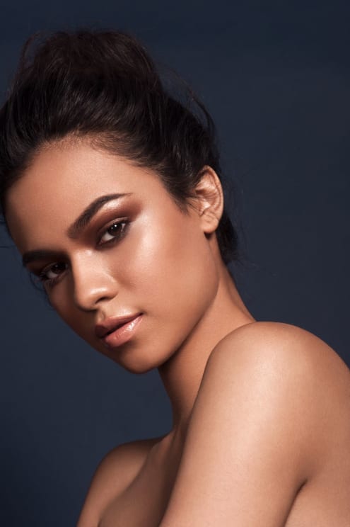 A Woman Poses With Bare Shoulders And Her Hair Up