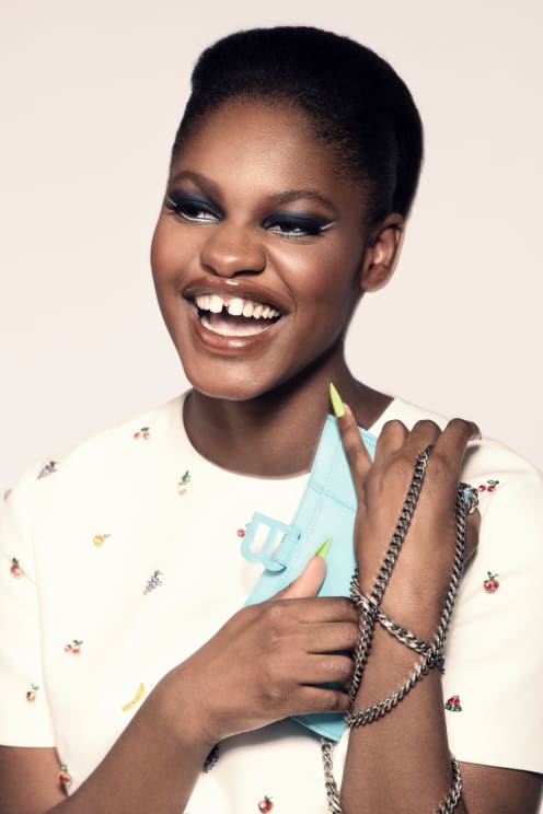 A Smiling Woman Holding A Blue Bag With Silver Chains