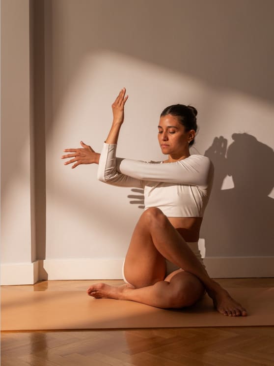 A Woman In White Sports Clothes Stretches Into A Yoga Pose On A Mat In A Room