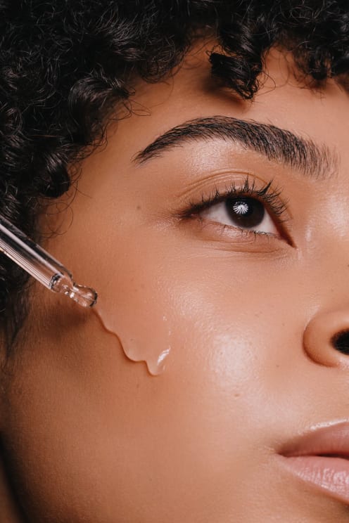 A Woman Applying A Liquid To Her Face