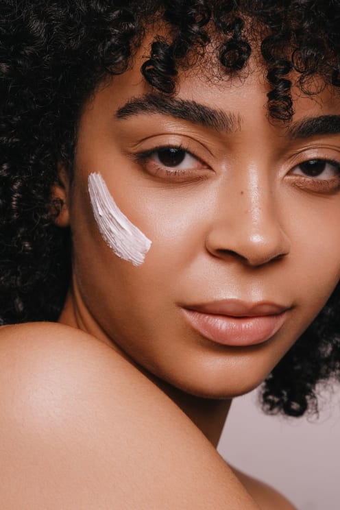 Portrait Of A Young Woman With Curly Hair With Cream On Her Face