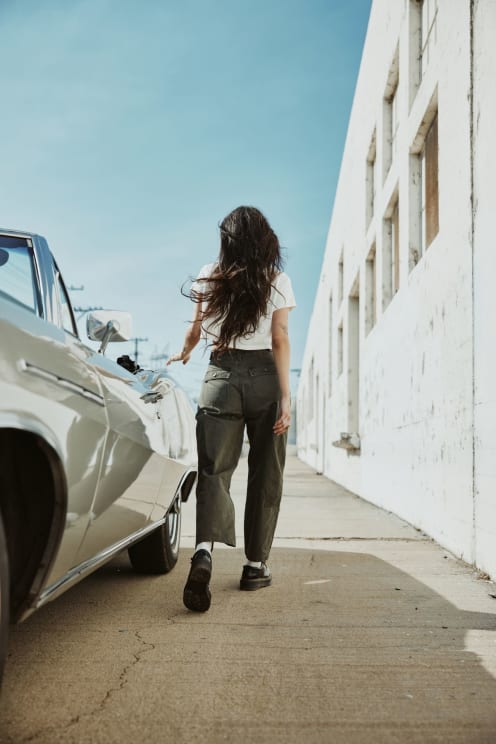 A Person Walking Down A Straight Next To Car