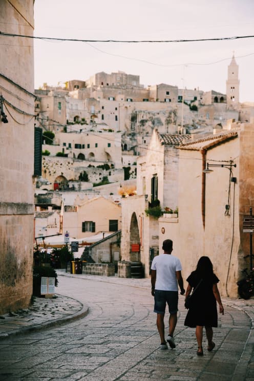 Two People Walking Down A Street