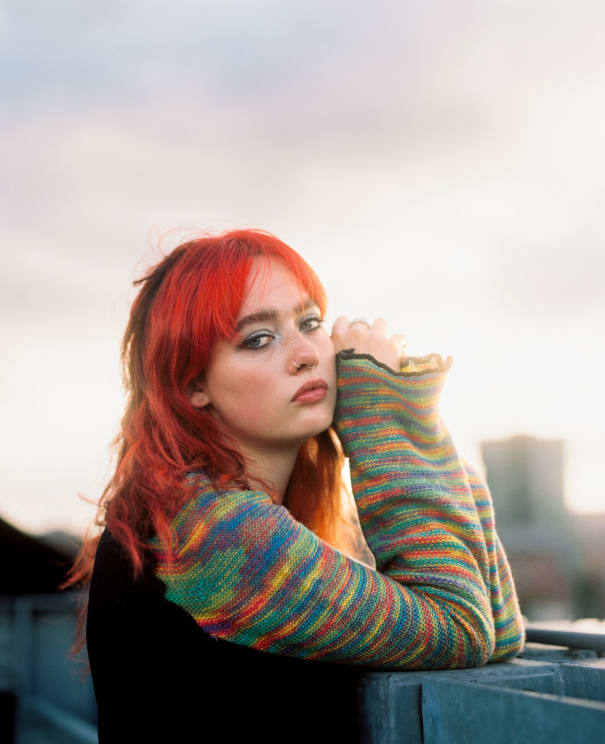 Portrait Of A Teenage Girl With Dyed Orange Hair Who Wears A Rainbow-colored Sweater